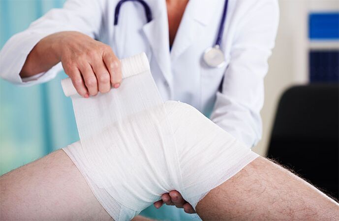 doctor bandaging the knee joint with osteoarthritis